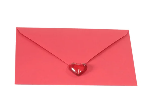 Красный конверт с пластиковым сердцем — стоковое фото