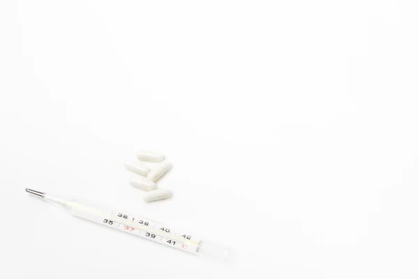 Termômetro e comprimidos brancos — Fotografia de Stock