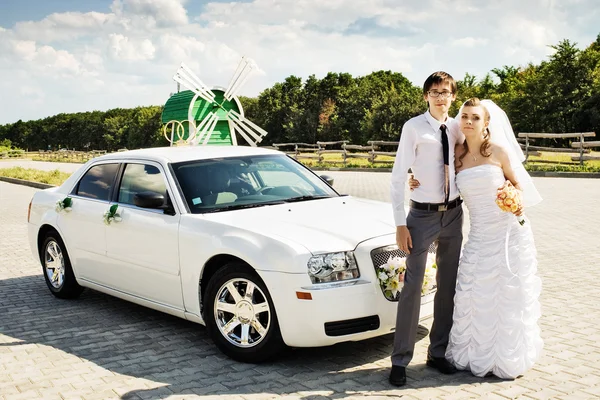 Novia y novio con un coche blanco — Foto de Stock