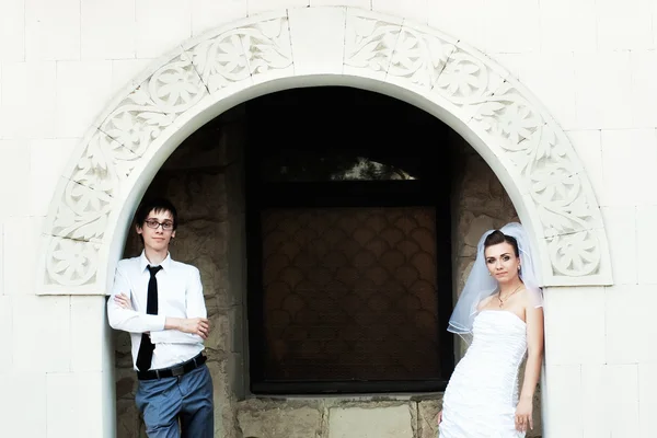 新婚夫婦がアーチのレンガの壁に対して立つ — ストック写真