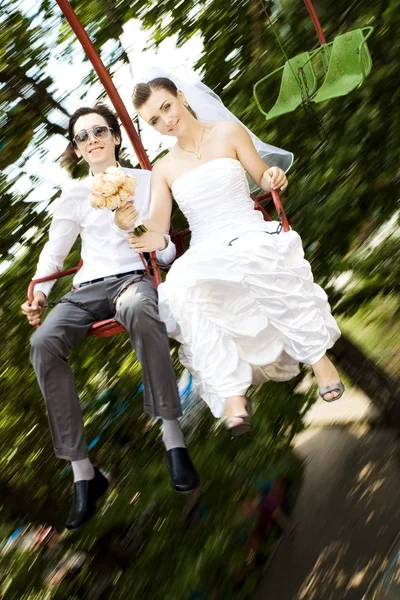 Nevěsta a ženich předení na karuselu — Stock fotografie