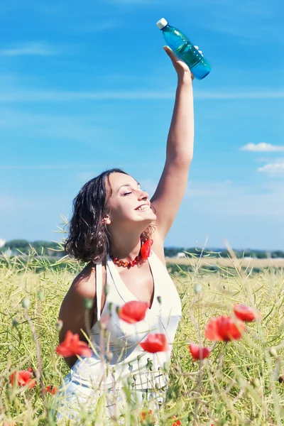 Girl holding bottle on poppy field — Stock Photo, Image
