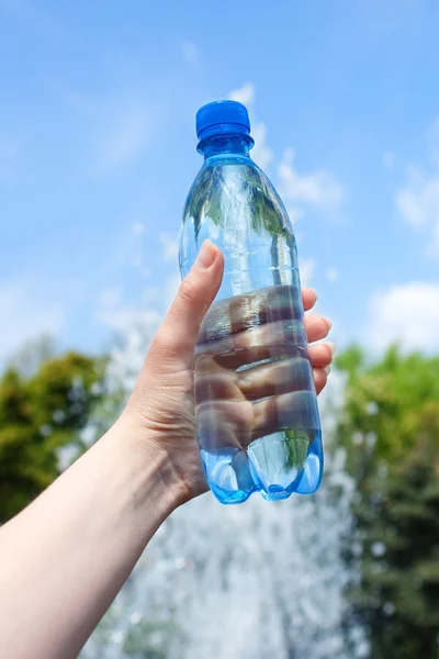 Botella azul con agua contra fuente borrosa — Foto de Stock