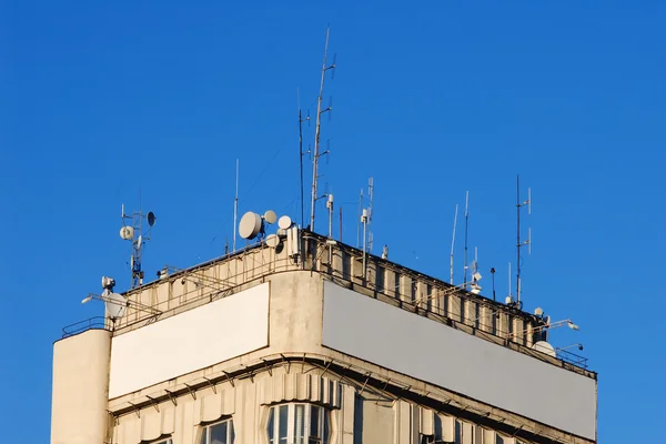 Parte superior de un edificio con antenas y carteles en blanco —  Fotos de Stock
