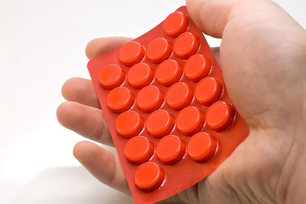 Embalagem de mão com comprimidos vermelhos — Fotografia de Stock