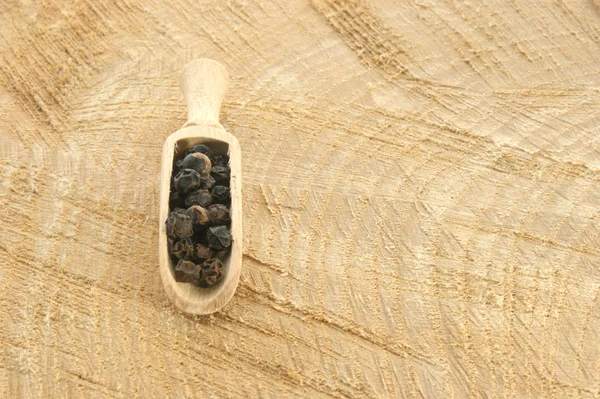 Pimenta preta em uma pá de madeira — Fotografia de Stock