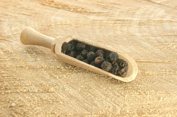 Черный перец в деревянной лопате — стоковое фото