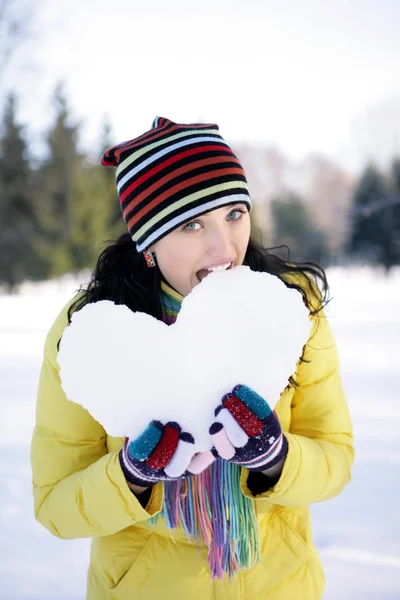 Девушка укусила снежное сердце — стоковое фото