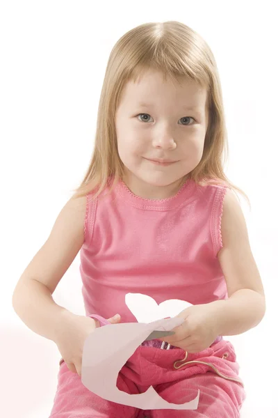 Menina pequena está cortando papel forma do coração — Fotografia de Stock