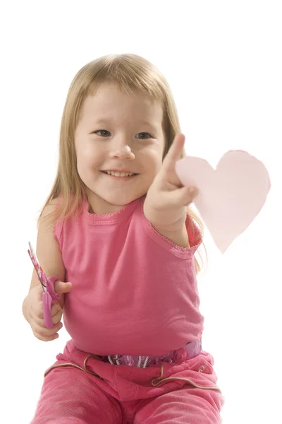 Menina pequena está cortando papel forma do coração — Fotografia de Stock