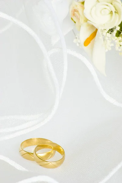 Wedding rings and flowers over veil — Stock Photo, Image