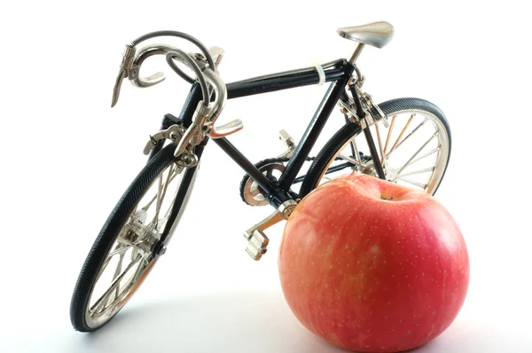Велосипед рядом с красным яблоком — стоковое фото