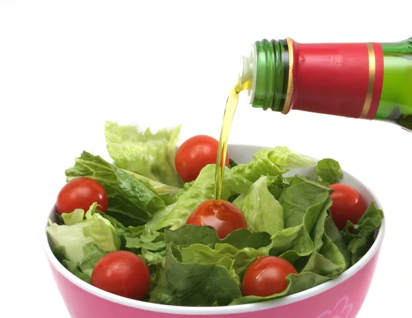 Оливковое масло льется на зеленый салат — стоковое фото