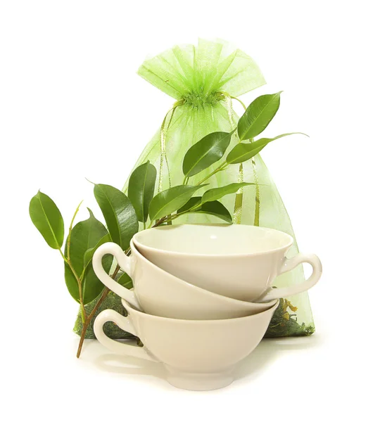 Tasses en porcelaine, feuilles et un sac de thé — Photo