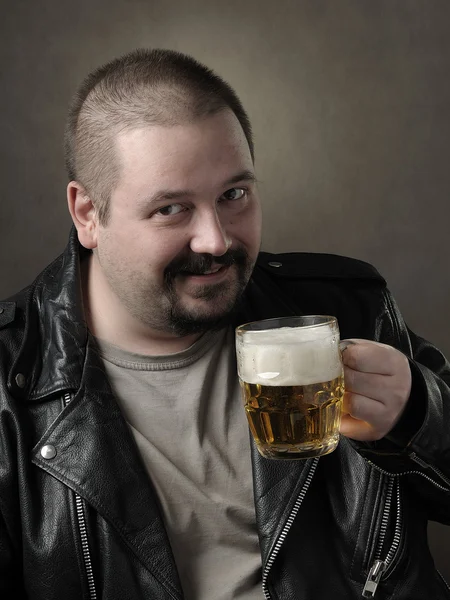 Mannen dricker öl från en mugg Stockbild
