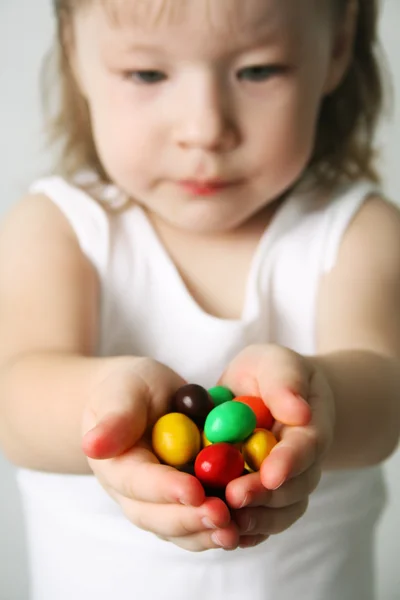 Small girl the hands the candies — Stock Photo, Image