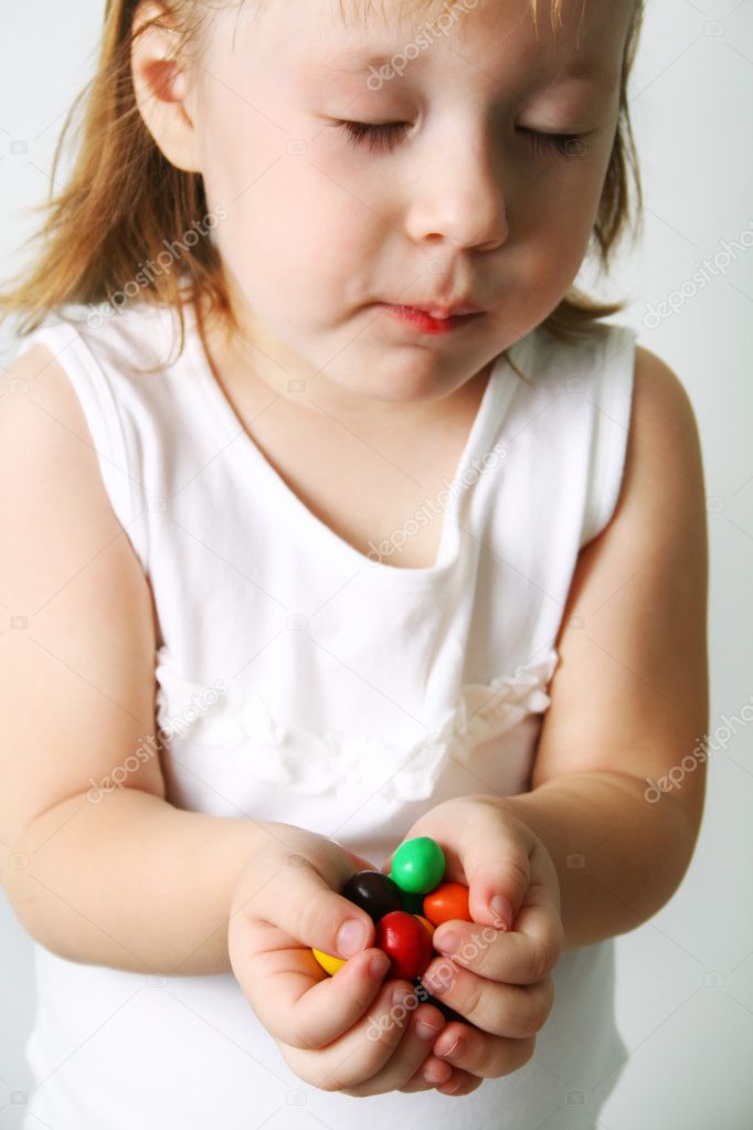 Small girl chews the candies