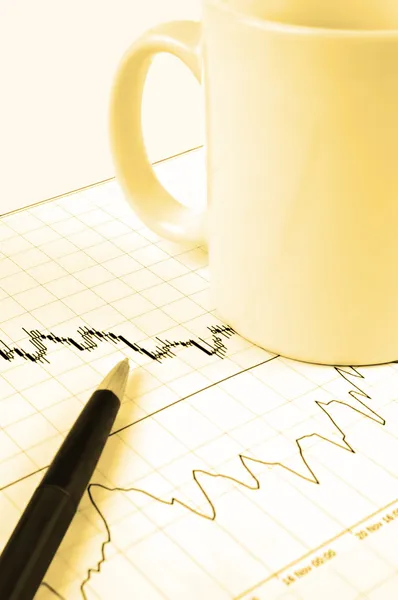 Перо и чашка на биржевом графике — стоковое фото