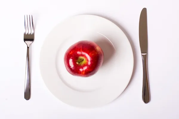Red apple on white plate — Stock Photo, Image