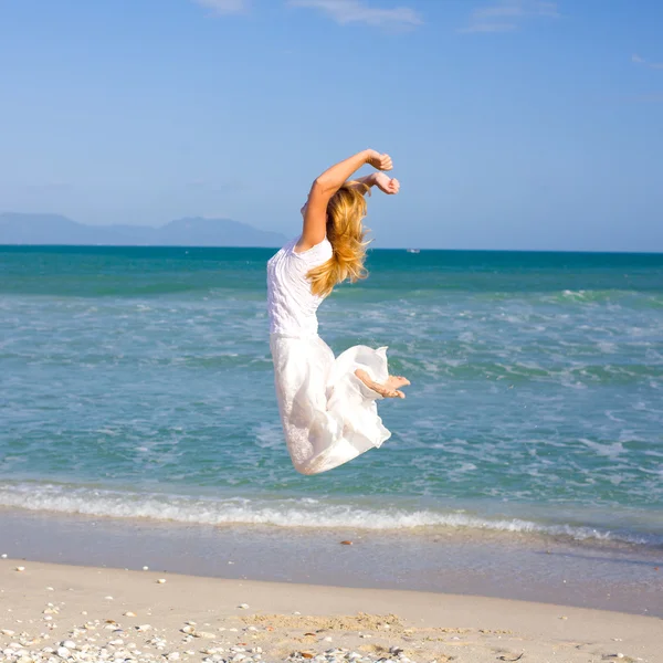 Жінка стрибає на пляжі — стокове фото
