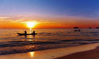 Seascape with kayakers at sunset clipart