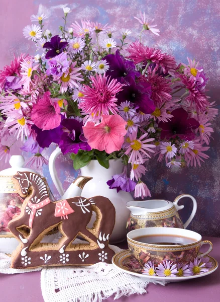 Cup of tea and a bouquet of flowers in a white jug — Stock Photo, Image