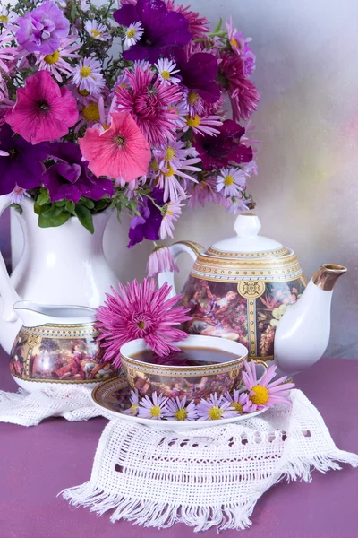 stock image Cup of tea and a bouquet of flowers in a white jug