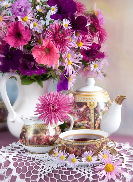 Cup of tea and a bouquet of flowers in a white jug — Stock Photo, Image
