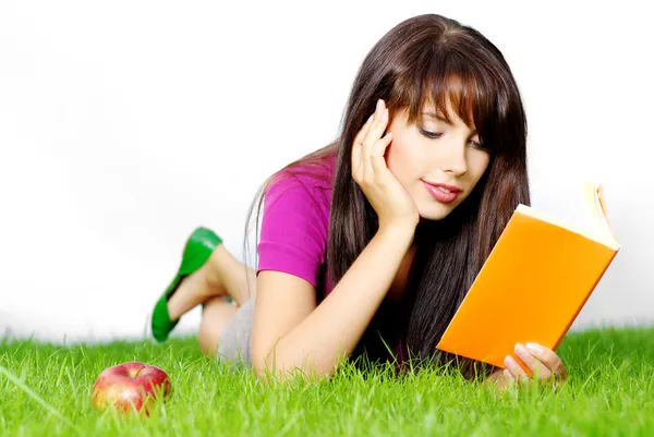 Kvinnan lägger på grönt gräs med bok — Stockfoto