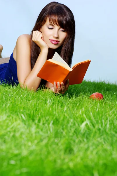 Mulher coloca na grama verde com livro — Fotografia de Stock