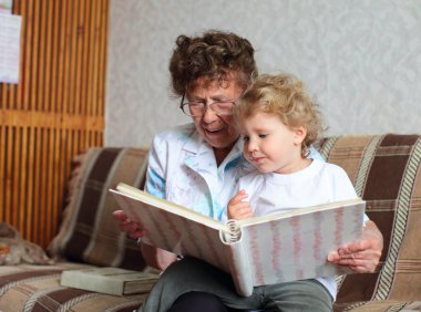 Grandmother reading book to the granddaughter clipart