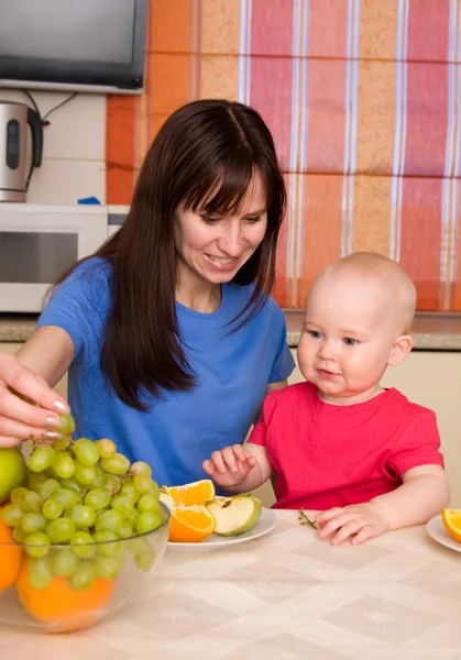 Прекрасная счастливая мама с сыном едят фрукты — стоковое фото