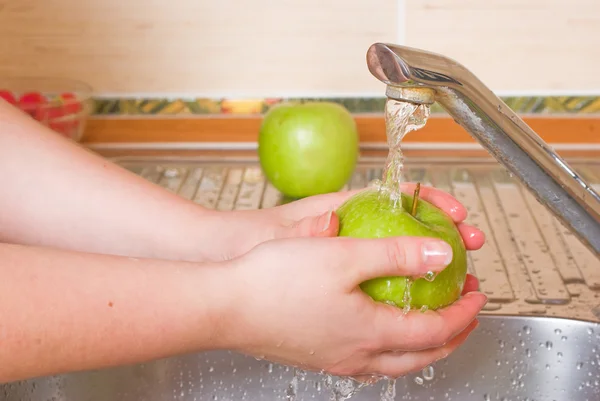 La mujer lava una manzana verde — Foto de Stock