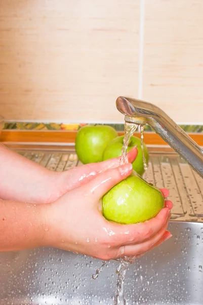 La mujer lava una manzana verde — Foto de Stock