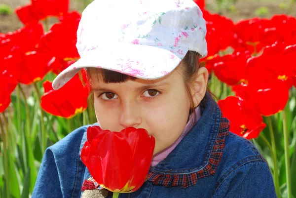 Pretty child with red tulips — Stock Photo, Image