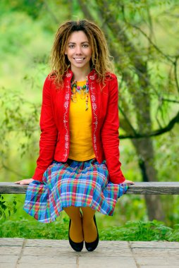 Girl with dreadlocks sits on bench clipart