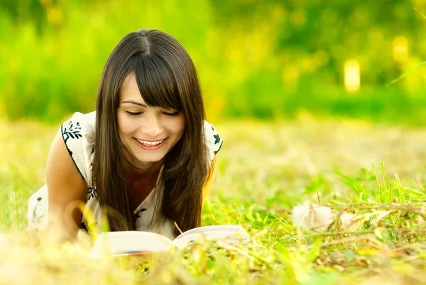 女の子は牧草地に本を読みます — ストック写真