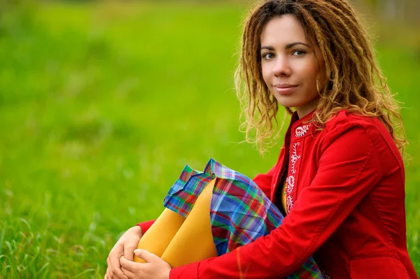 Girl with dreadlocks sits on grass — Stock Photo, Image