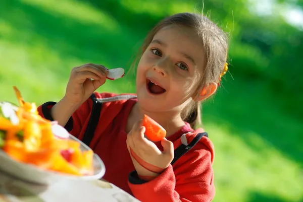 Девушка ест помидор и садовую редиску — стоковое фото