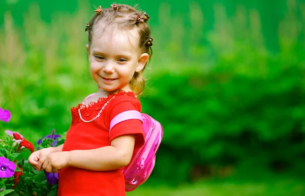 Girl with a backpack about florets — Stock Photo, Image