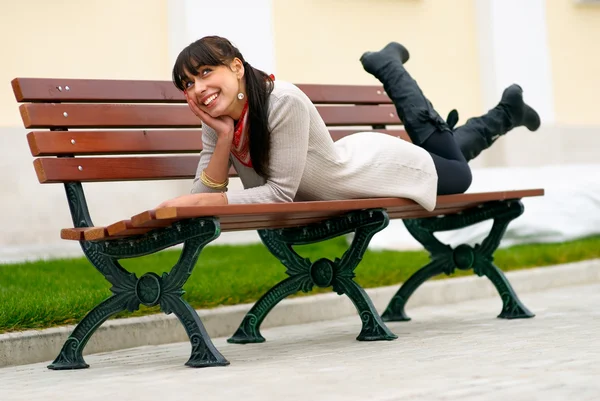 Beautiful girl lays on bench — Stock Photo, Image