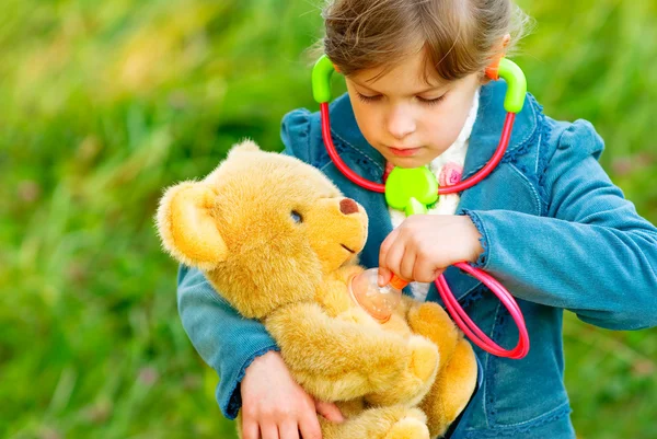 Девушка слушает стетоскоп плюшевого медведя — стоковое фото