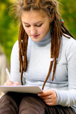 Girl writes on sheet of paper clipart