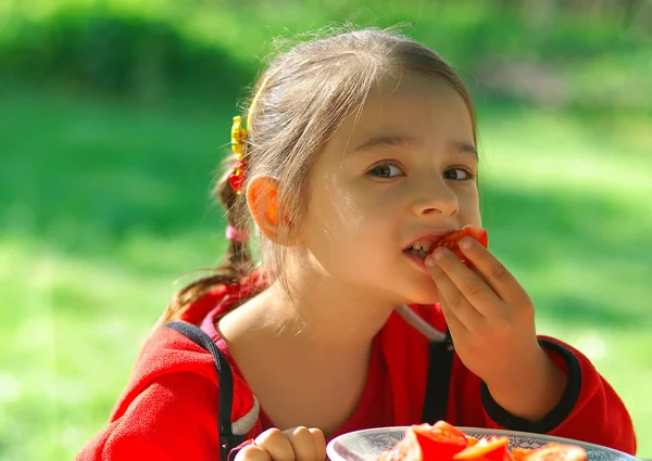Girl bites tomato — Stock Photo, Image