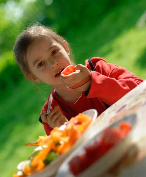 Das Mädchen isst eine Tomate — Stockfoto