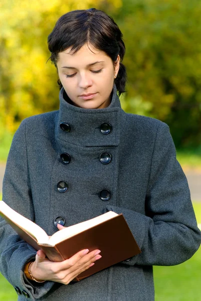 Lány kabát elolvassa a könyvet — Stock Fotó