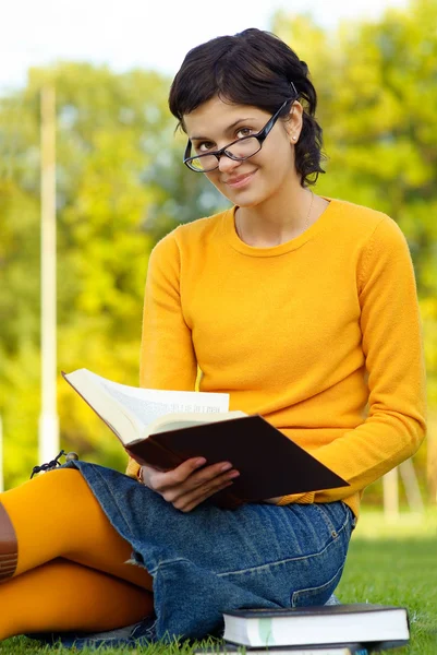 女の子は芝生の上の本を読みます — ストック写真