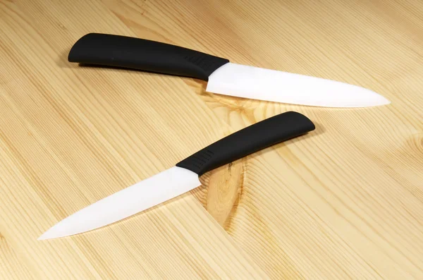 Набор белых керамических ножей на деревянной доске — стоковое фото