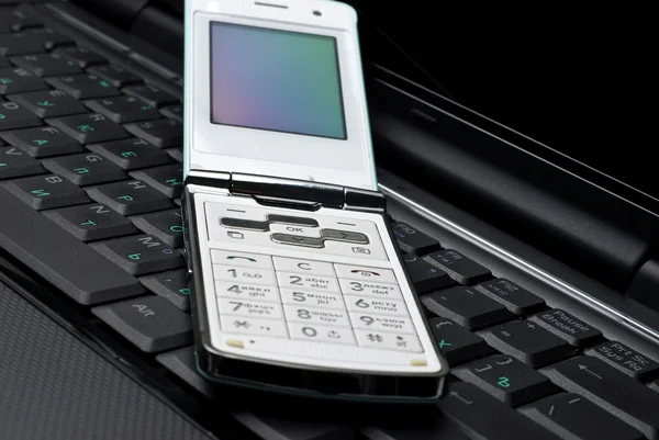 Mobiele telefoon op een laptop — Stockfoto