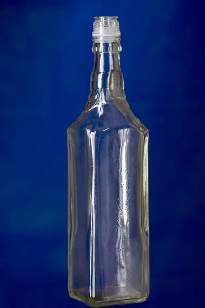 Lege glazen fles op blauw — Stockfoto